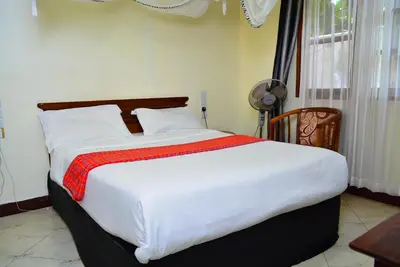a bedroom with a large bed with white sheets and red blanket at Destination 3Degrees Hotel in Arusha