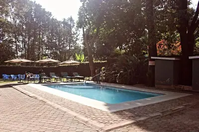a swimming pool in a yard with chairs and umbrellas at Destination 3Degrees Hotel in Arusha