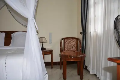 a bedroom with a canopy bed and a chair at Destination 3Degrees Hotel in Arusha