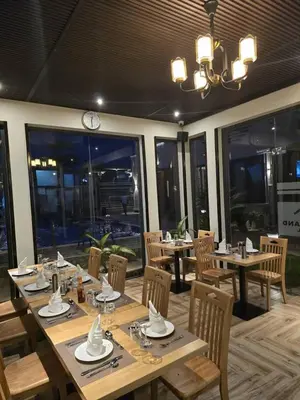 a restaurant with wooden tables and chairs and windows at Primeland Hotel in Moshi