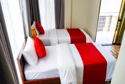 two beds in a hotel room with red and white sheets at Primeland Hotel in Moshi