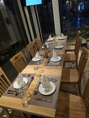 a long wooden table with plates and napkins on it at Primeland Hotel in Moshi