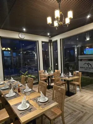 a restaurant with wooden tables and chairs and windows at Primeland Hotel in Moshi