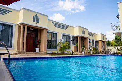 a villa with a swimming pool in front of a building at Primeland Hotel in Moshi