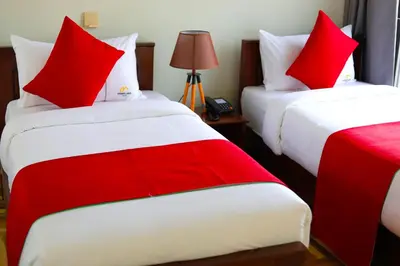a hotel room with two beds with red pillows at Primeland Hotel in Moshi