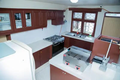 a kitchen with wooden cabinets and a stove top oven at B&B HOTEL in Moshi