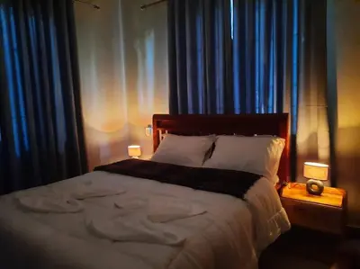 a bedroom with a large bed with blue curtains at Ellyz Home Stay in Moshi