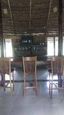 a table with three chairs and a piano in a room at Meru Mbega Lodge in Usa River