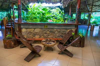 a bar in a restaurant with chairs and an aquarium at Meru Mbega Lodge in Usa River