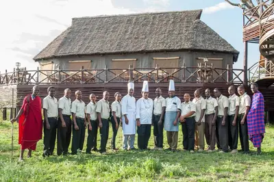 a group of people in uniforms standing in front of a building at Lake Ndutu Luxury Tented Lodge in Sinoni