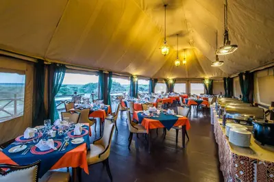a dining room with tables and chairs in a tent at Lake Ndutu Luxury Tented Lodge in Sinoni