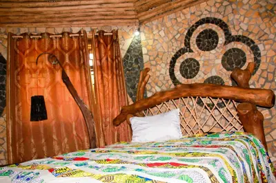 a bedroom with a bed with a wooden head board at Songota Falls Lodge in Arusha