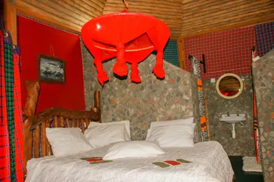 a bedroom with a bed with a red curtain over it at Songota Falls Lodge in Arusha