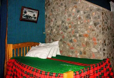 a bed in a room with a stone wall at Songota Falls Lodge in Arusha