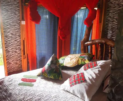 a bedroom with a bed with pillows on it at Songota Falls Lodge in Arusha