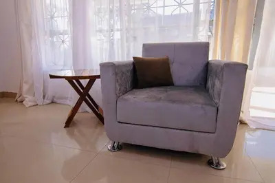 a chair sitting next to a table in a room at venem house in Kisongo