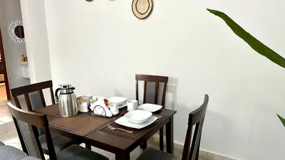 a dining room table with chairs and a table and a clock at Mvule Homes in Arusha