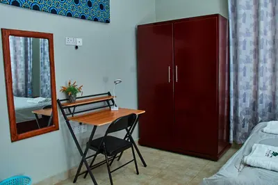 a room with a desk and a cabinet and a mirror at Mvule Homes in Arusha