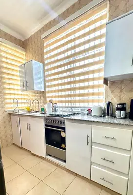 a kitchen with white cabinets and a stove top oven at Mvule Homes in Arusha