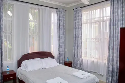 a bedroom with a bed and two large windows at Mvule Homes in Arusha
