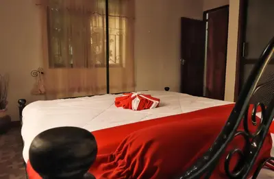 a bed with a red blanket and a bag on it at Msovi Hideaway in Arusha