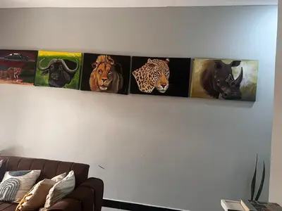 four pictures of animals on a wall above a couch at Sinana Escapes - Arusha in Arusha