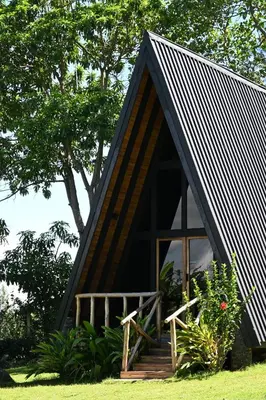 a small house with a black roof and a porch at Msitu Hut in Tuvaila