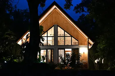 a house with large glass windows on the side of it at Msitu Hut in Tuvaila