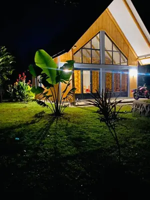 a house at night with a green lawn in front of it at Msitu Hut in Tuvaila