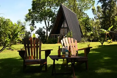 two chairs and a table in a yard with a house at Msitu Hut in Tuvaila