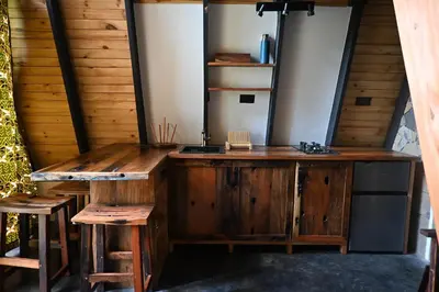a wooden desk with two stools in a room at Msitu Hut in Tuvaila
