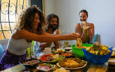 a group of people sitting around a table with food at BABA AFRICA HOSTEL in Arusha