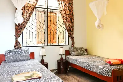 two beds in a room with a window at BABA AFRICA HOSTEL in Arusha