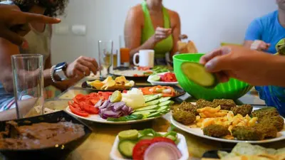 a group of people sitting around a table with plates of food at BABA AFRICA HOSTEL in Arusha