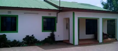 a small white house with a green roof at BABA AFRICA HOSTEL in Arusha