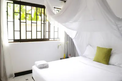 a bedroom with a white bed with a window at OYA Guest House in Usa River