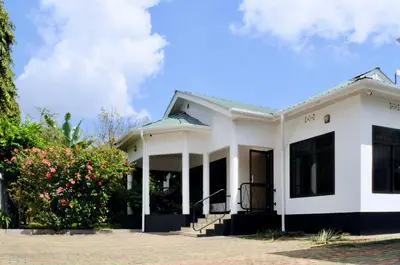 a white house with a porch at OYA Guest House in Usa River