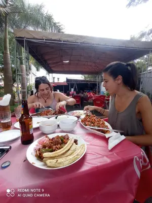 two women sitting at a table with plates of food at Janibichi Adventures hostel in Moshi