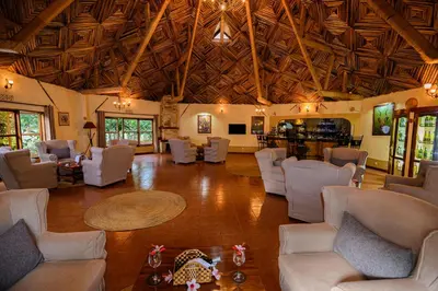 a large living room with white chairs and a table at KUDU LODGE & CAMPSITE in Karatu