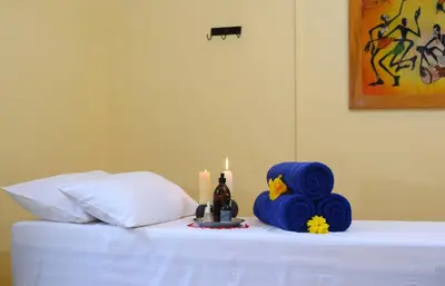 a table with a candle and a bottle of wine on a bed at KUDU LODGE & CAMPSITE in Karatu