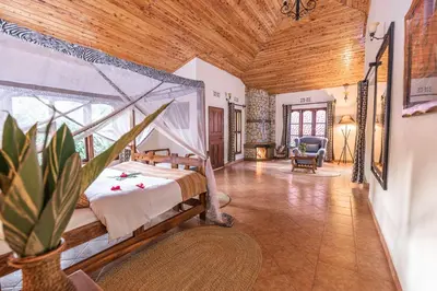 a bedroom with a bed and a chair in a room at KUDU LODGE & CAMPSITE in Karatu