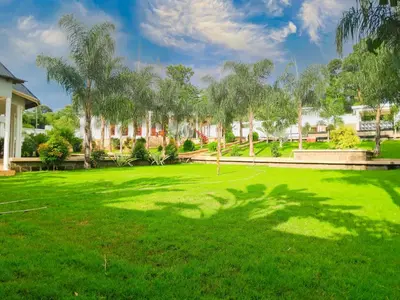 a large green yard with palm trees and a building at Hellen's Riverside villas in Moshi