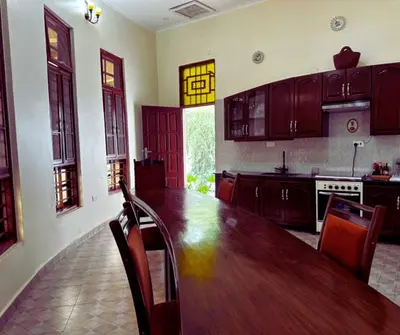 a large kitchen with a wooden table and chairs at Hellen's Riverside villas in Moshi