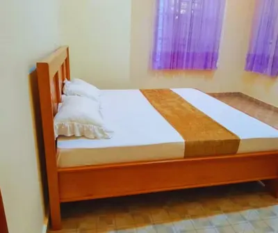 a wooden bed with white sheets and pillows in a bedroom at Hellen's Riverside villas in Moshi