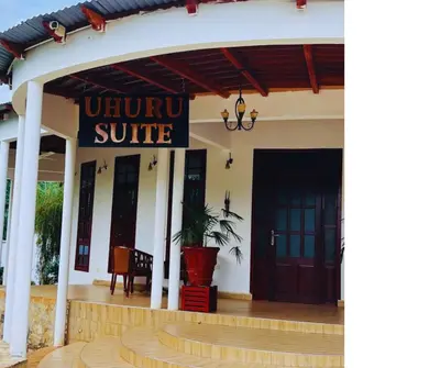a building with a sign that reads unique suite at Hellen's Riverside villas in Moshi