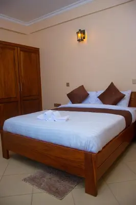 a bedroom with a large bed with white sheets at Aves Executive Hotel in Arusha