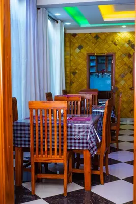 a dining room with a table and chairs and a tv at Aves Executive Hotel in Arusha