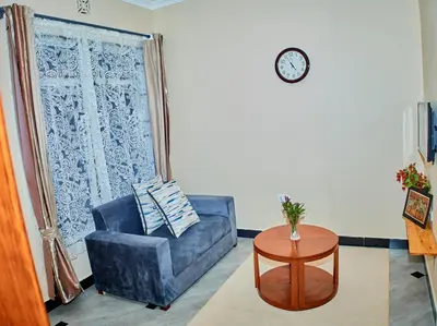 a living room with a blue chair and a table at Arusha Serene Apartments in Arusha