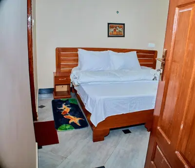 a bedroom with a bed with a wooden headboard at Arusha Serene Apartments in Arusha