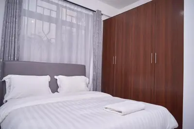 a bedroom with a large bed with a wooden cabinet at Diamond Apartments in Arusha